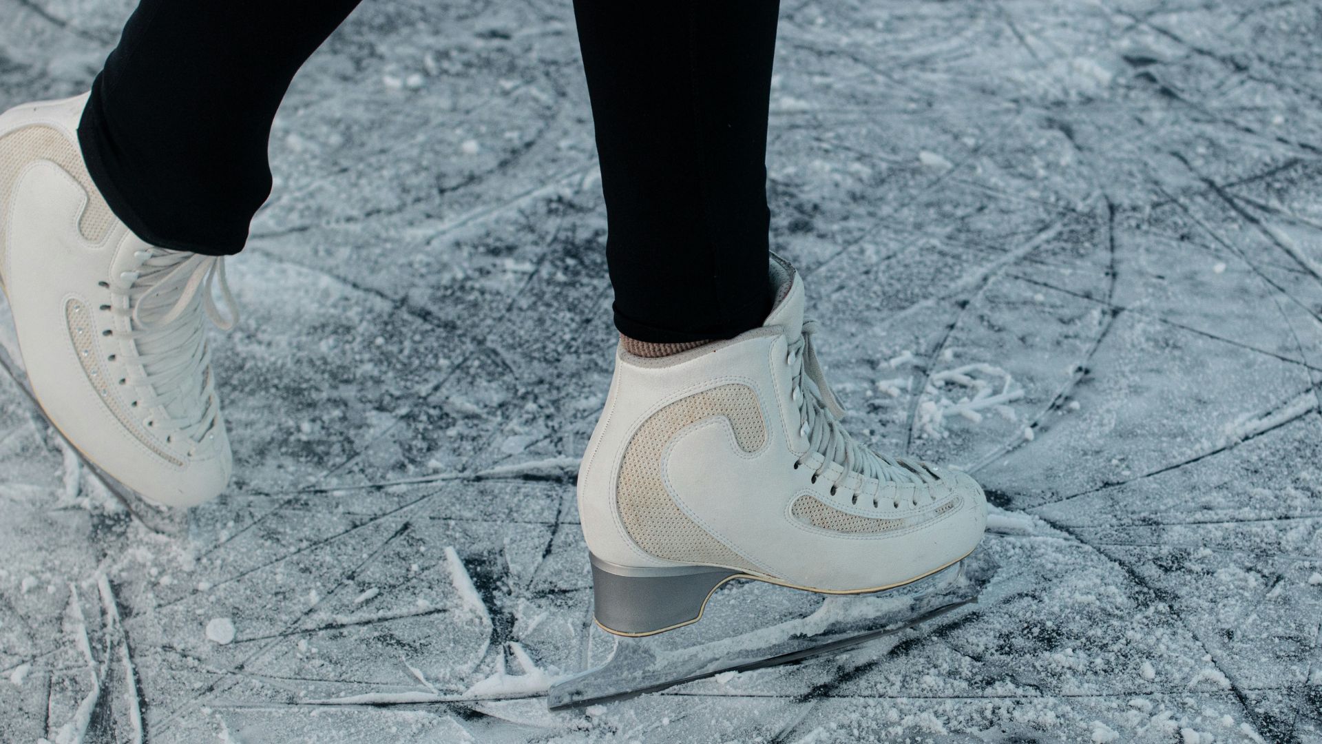 Close up of person skating on frozen ice rink.
